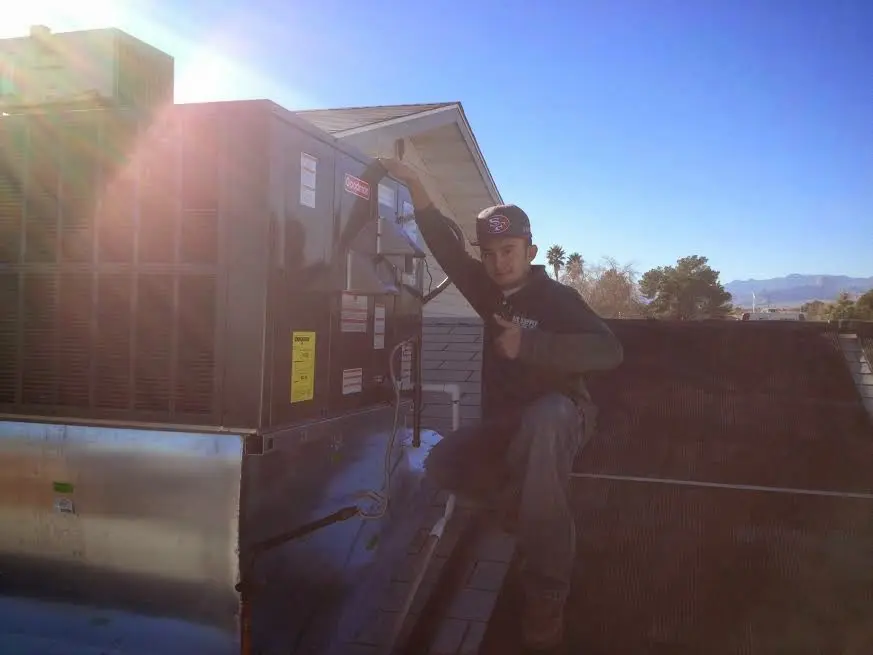 HVAC technician performing Heat Pump Repair on a rooftop unit in Fishhook