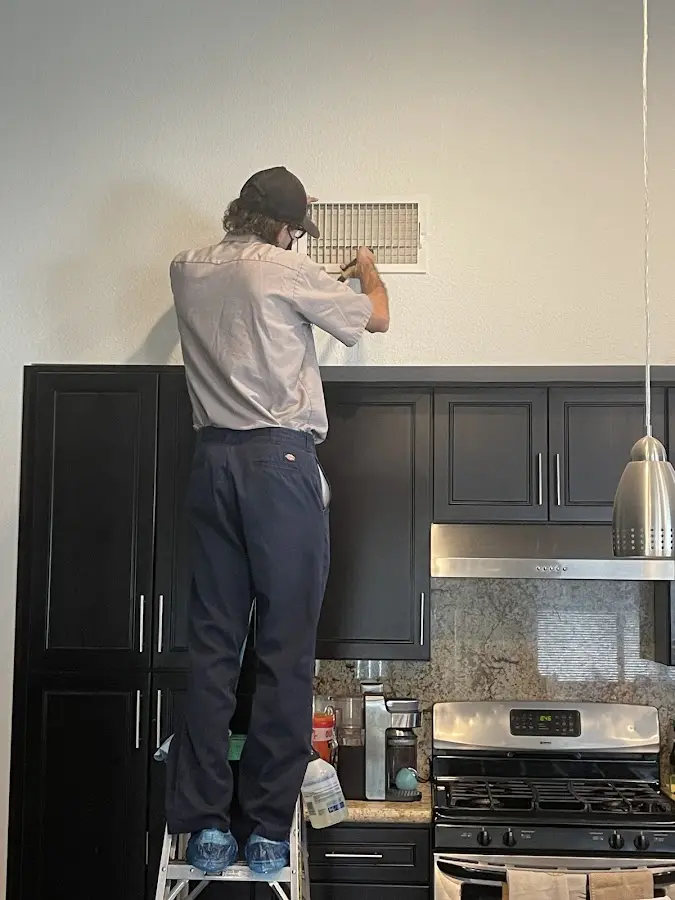 Technician inspecting an air vent during HVAC service in Fishhook